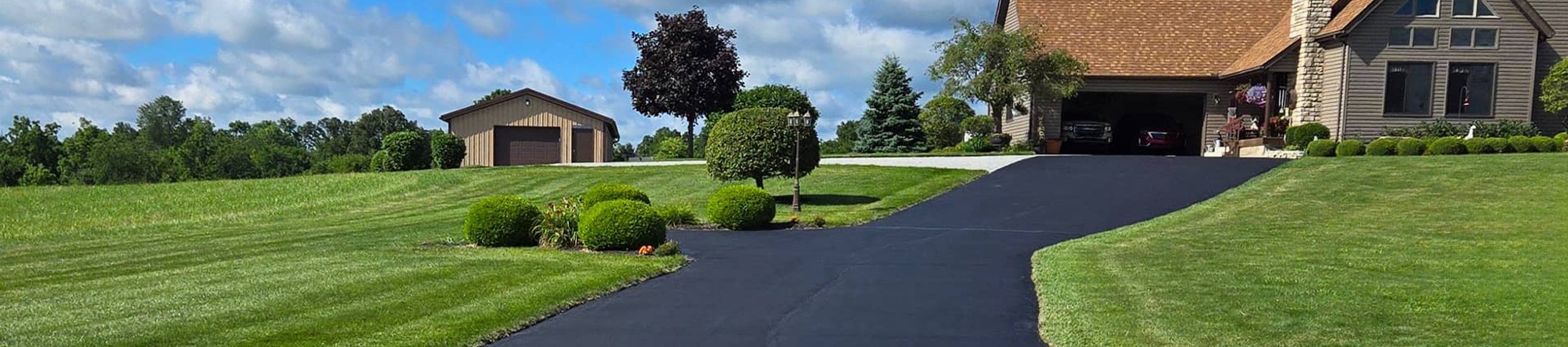 Freshly sealed residential driveway leading to a home in Bellefontaine, OH