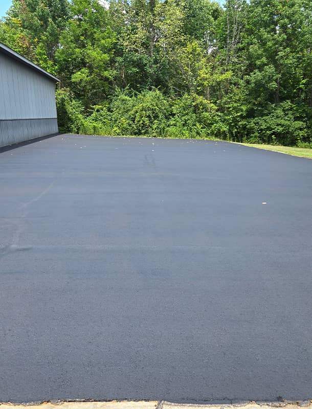 Freshly sealed asphalt pad beside a metal building in Delaware, OH