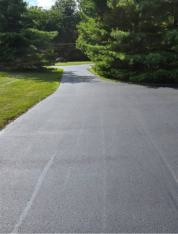 Smooth black asphalt driveway winding through a yard in Ostrander, OH