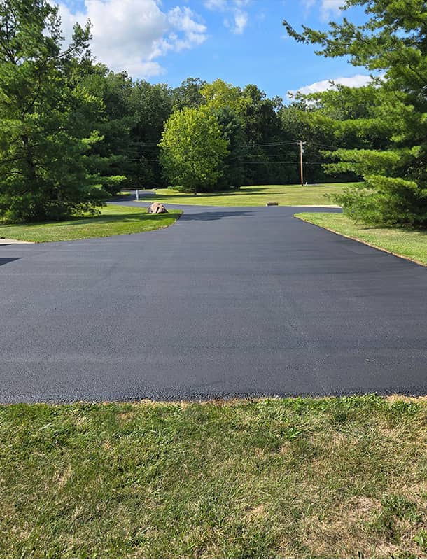 Wide freshly sealed driveway apron at an Ostrander, OH home